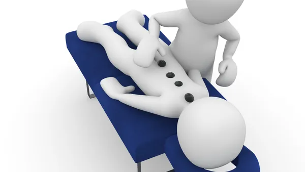 Physiotherapeut behandelt den Rücken eines liegenden Patienten